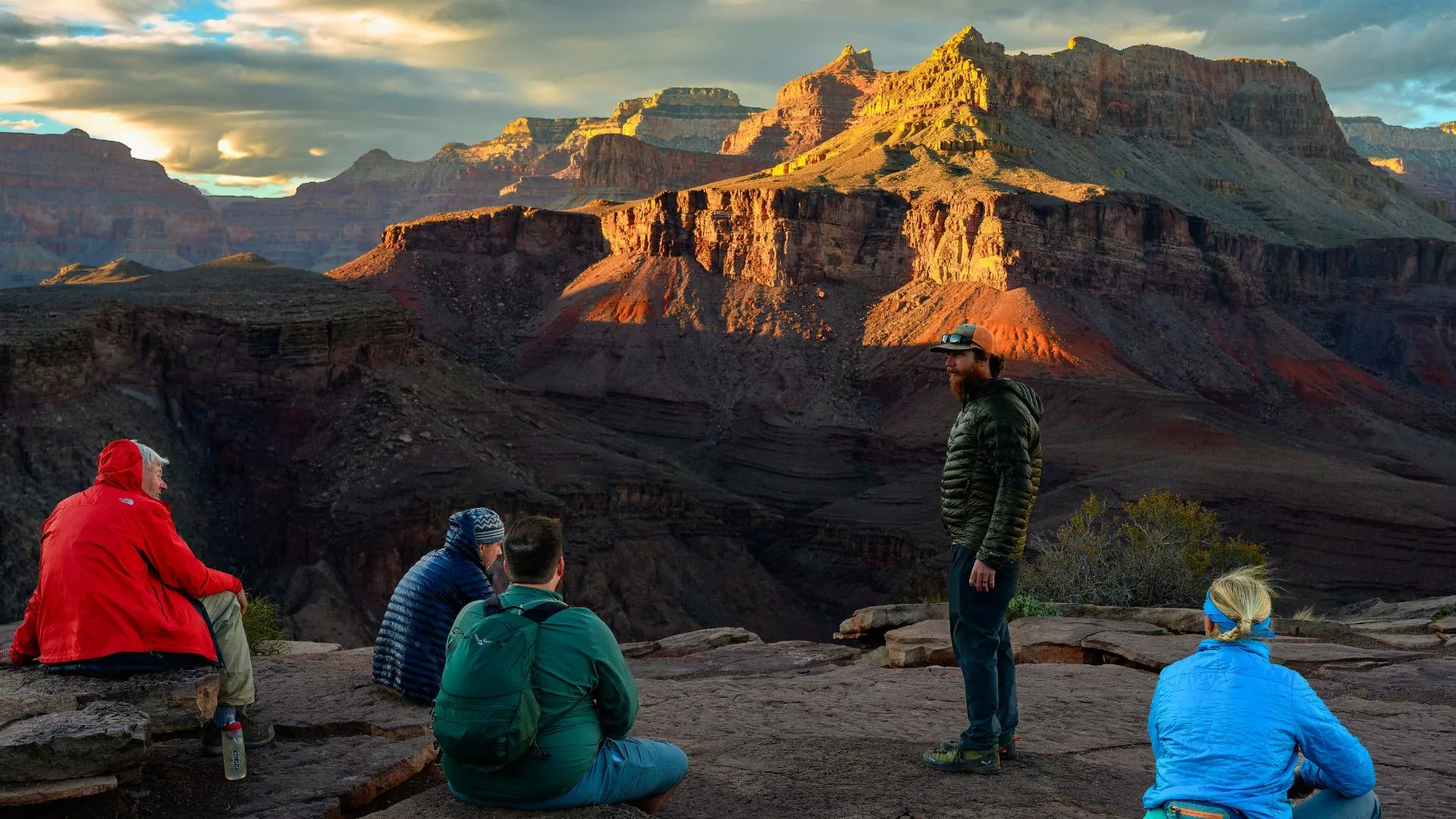 Μια ομάδα κάθεται στο Grand Canyon κοιτάζοντας έξω από την θέα